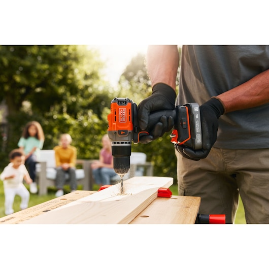A wooden plank being drilled into using the BLACK+DECKER® POWERCONNECT™ 18V Cordless Hammer Drill.