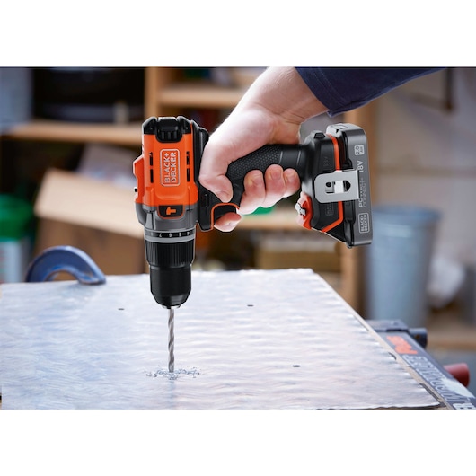 A metal sheet being drilled into using the BLACK+DECKER® POWERCONNECT™ 18V Cordless Hammer Drill.