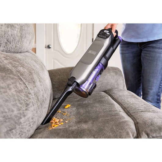 BLACK+DECKER SUMMITSERIES Cordless Stick Vacuum vacuuming crumbs off couch with crevice tool
