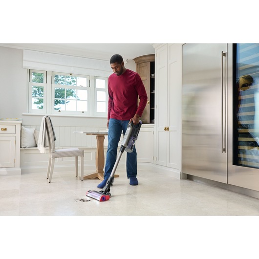 A man vacuums soil from a tile floor with the BLACK+DECKER® SUMMITSERIES™ select Cordless Stick Vacuum.