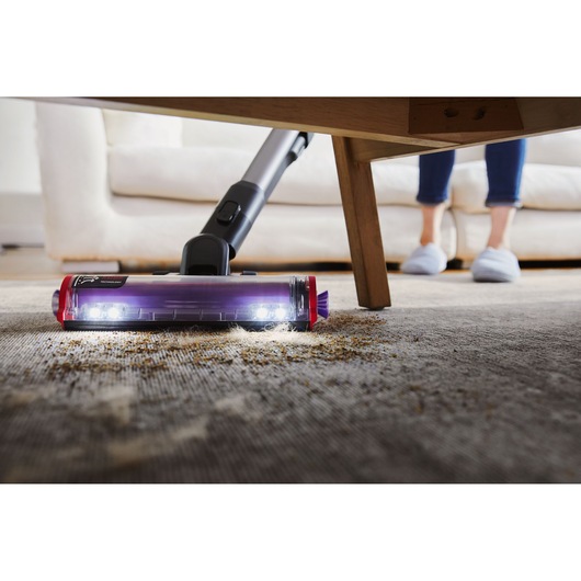BLACKDECKER BHFEA640WG cordless vacuum cleaning debris under a table on carpet with LED lights on the floor head.