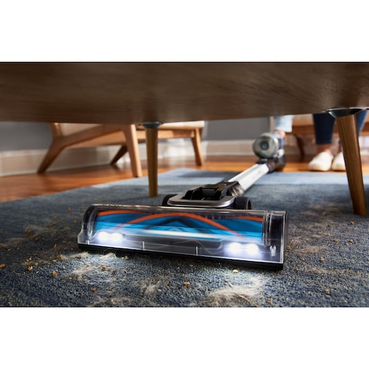 POWERSERIES Extreme MAX vacuuming up dust under a table with the LED headlights on