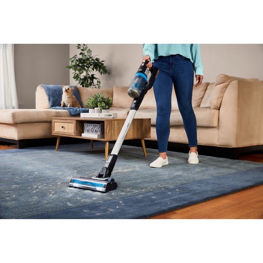 BLACKDECKER BHFEB520D1 cordless stick vacuum cleaning a blue rug in a living room setting.