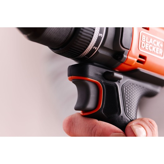 Close-up photo of BLACK+DECKER BLD682XN drill handle and trigger in hand, showing textured black and orange grip.