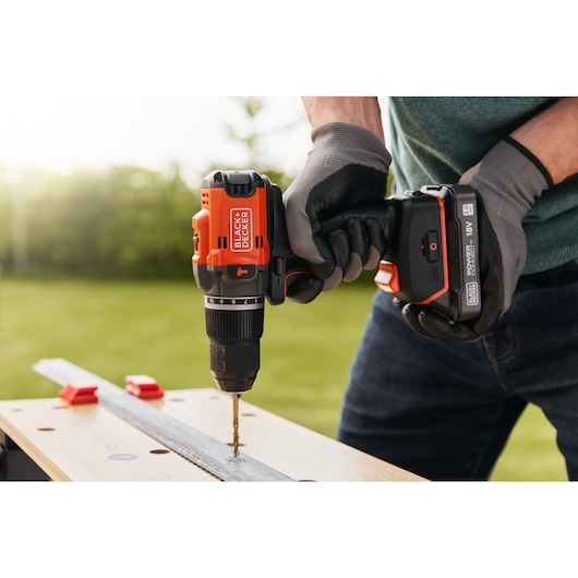 A metal plank being drilled into using the BLACK+DECKER® 18V POWERCONNECT™ Brushless Hammer Drill.