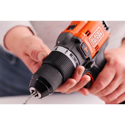 Close-up photo of BLACK+DECKER cordless drill BLD683XN, black and orange, held by two hands during use.