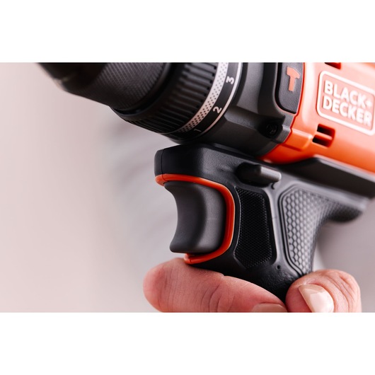Close-up photo of BLACK+DECKER BLD683XN power drill handle and trigger in hand, showing textured black and orange grip.