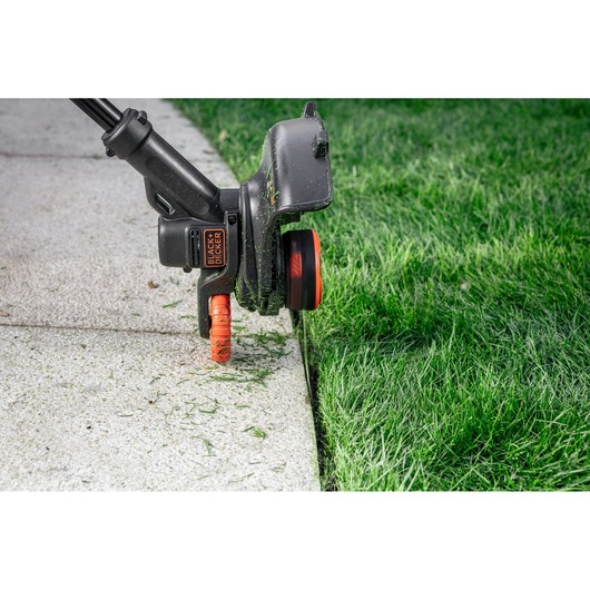 BLACK+DECKER BZOB2S1 grass trimmer cutting lawn edge next to pavement, close-up photo.