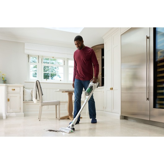 A man vacuums soil from a tile floor using the BLACK+DECKER® 18V reviva™ POWERCONNECT™ Stick Vacuum.