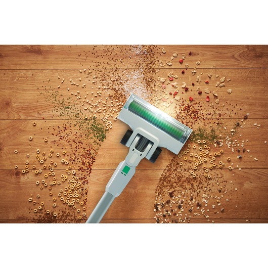 Close-up of debris on a wooden floor being vacuumed by the BLACK+DECKER® reviva™ 18V POWERCONNECT™ Cordless Stick Vacuum.