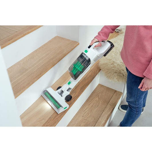 Wooden steps being vacuumed by the BLACK+DECKER® reviva™ 18V POWERCONNECT™ Cordless Stick Vacuum in handheld mode with floorhead.