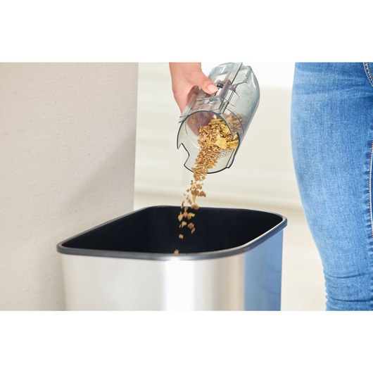 The dustbowl of the BLACK+DECKER® reviva™ 18V POWERCONNECT™ Cordless Stick Vacuum being emptied into a bin.
